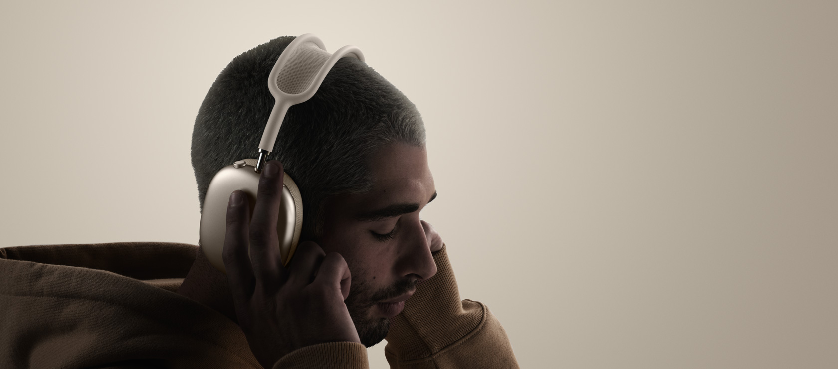 AirPods Max 2ヘッドフォンを装着した人物を横から見た図。イヤークッションに手で触れている