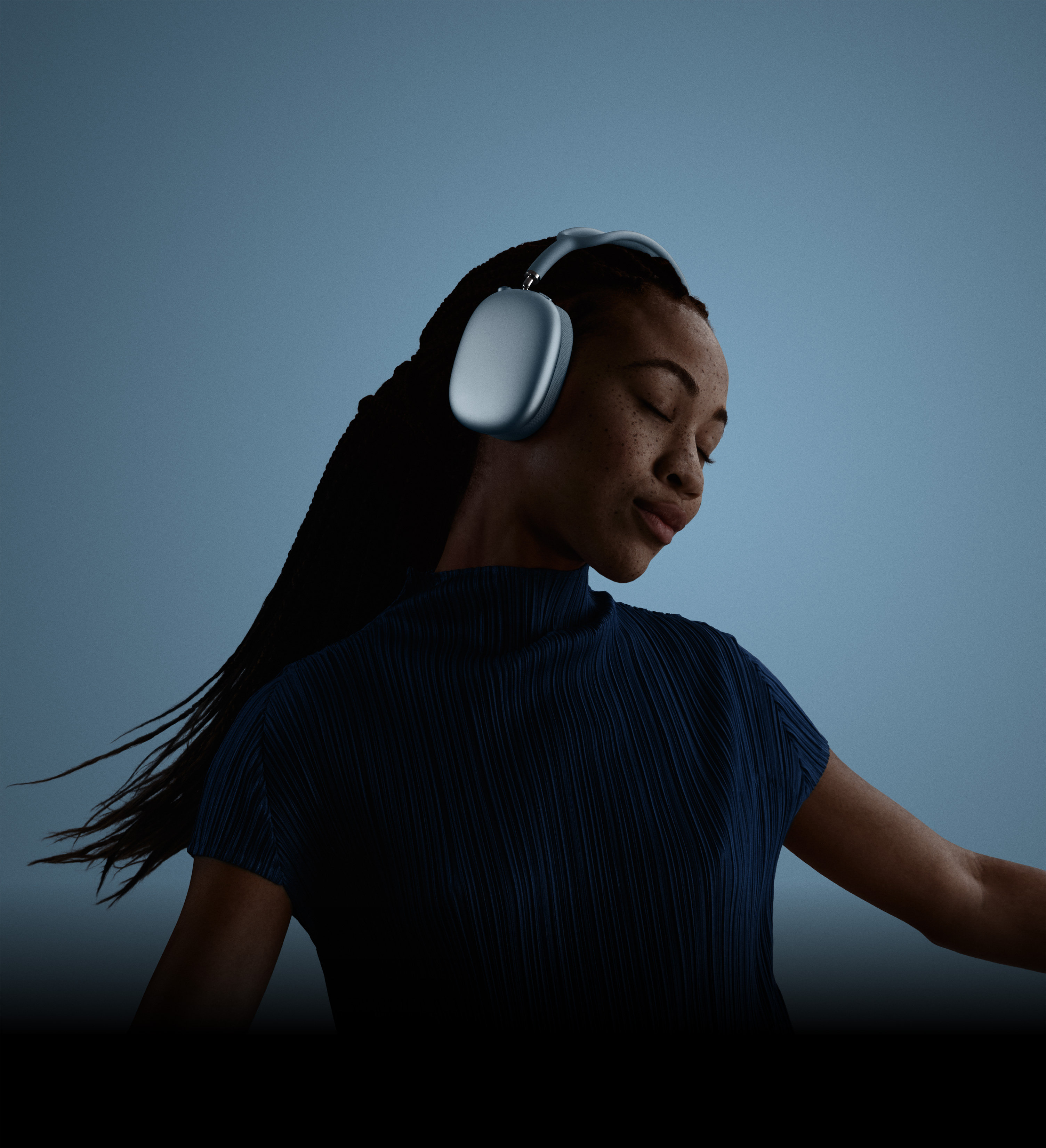 目を閉じて頭を傾けている人物の横顔。ブルーのAirPods Max 2ヘッドフォンを装着している