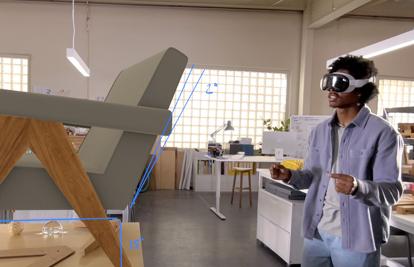Apple Vision Proを装着した人物が、手の動きを使って椅子の3D投影図の大きさを測っている