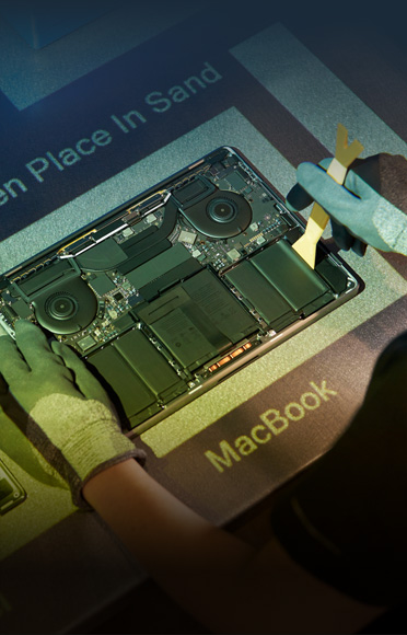 手袋をはめた手がMacBookを分解している。内部の部品が見えている