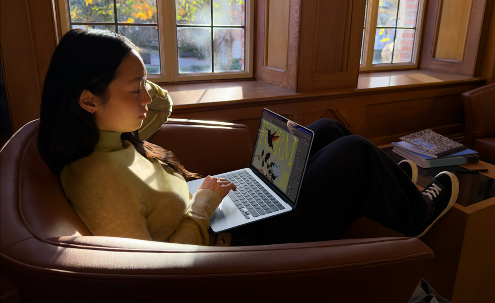 椅子に座ってMacBook Airを使っている人物