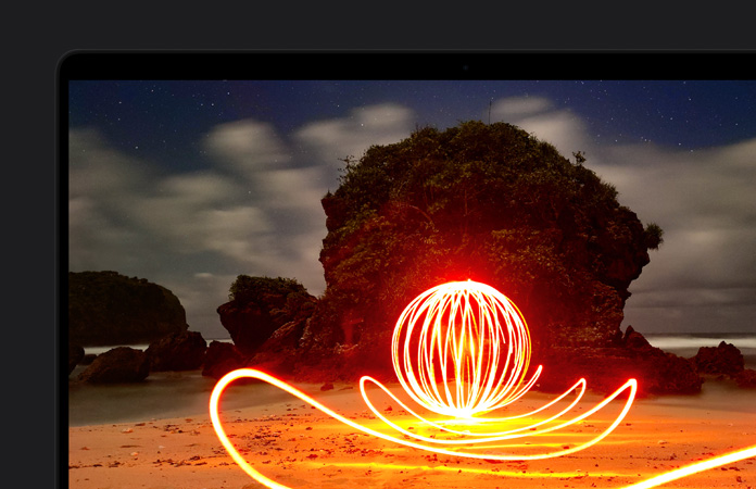 MacBook Proの画面に、浜辺で強い光を放つインスタレーションアートが映し出されている。Extreme Dynamic Rangeによるディスプレイのコントラストを示している